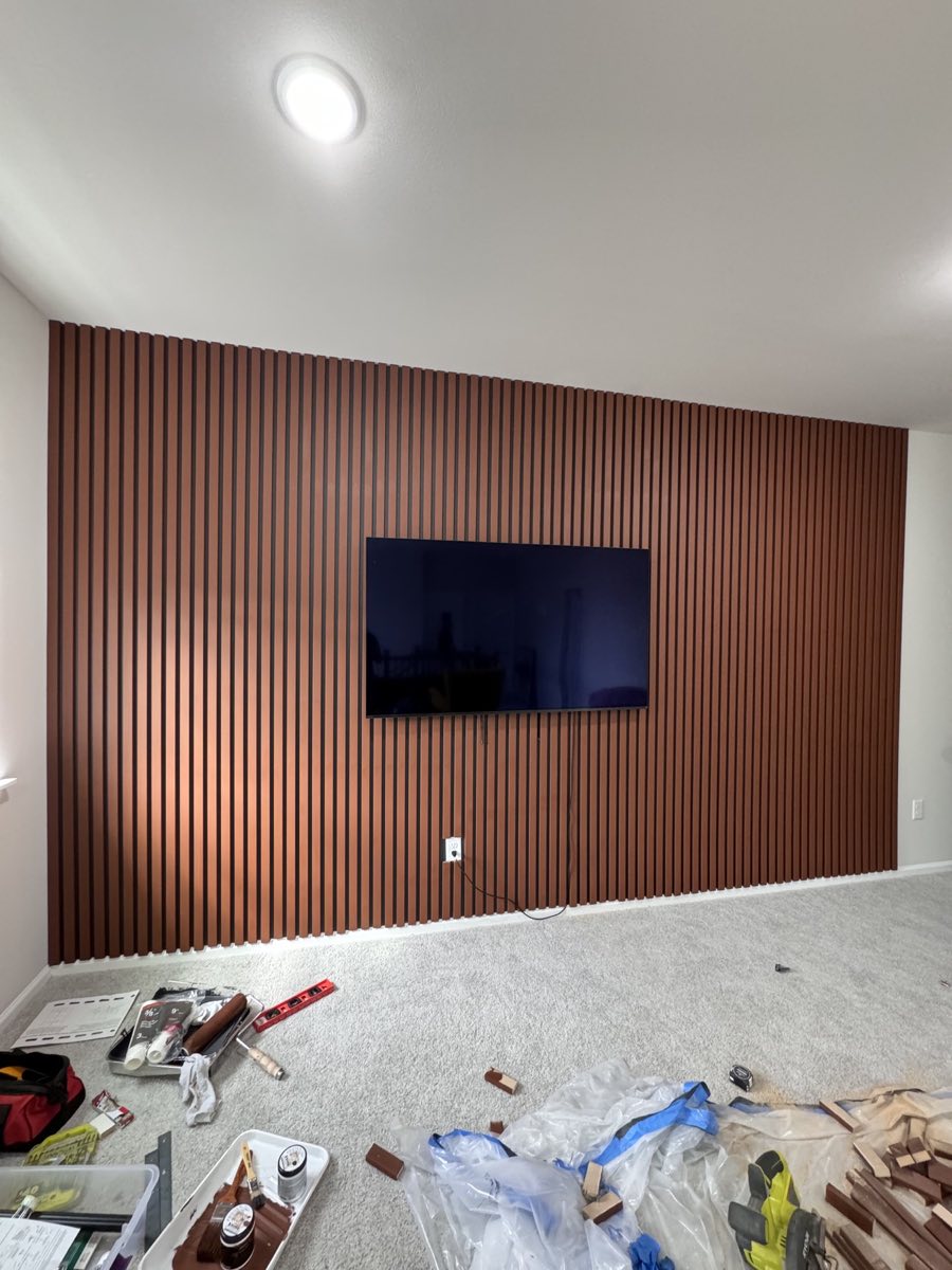 Walnut slat wall during installation with tools and materials visible