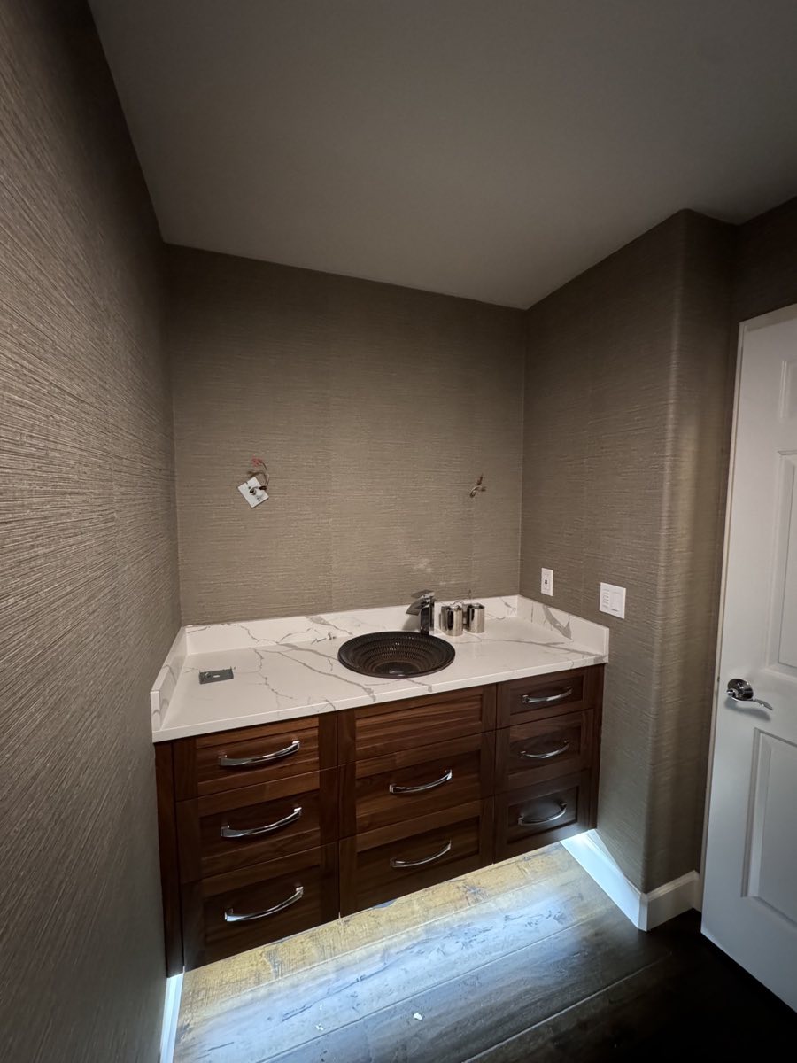 Textured taupe wallcovering installed around a bathroom vanity
