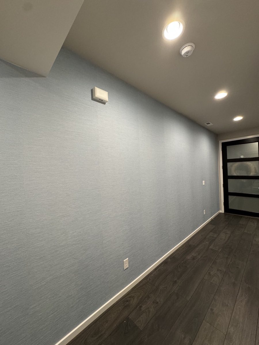 Blue textured wallcovering installed along a finished entry corridor