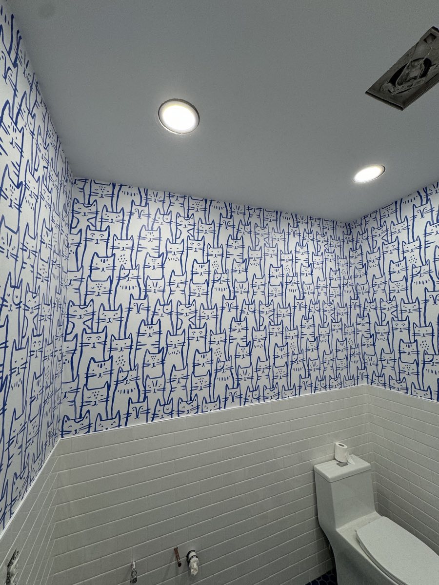 Blue cat pattern wallpaper installed above tiled bathroom walls