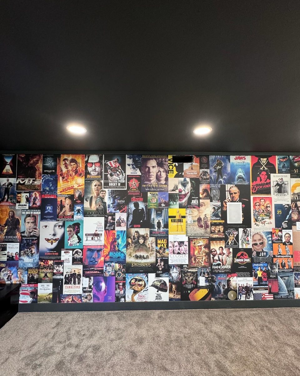 Wide view of a cinema poster wall covering a finished media room